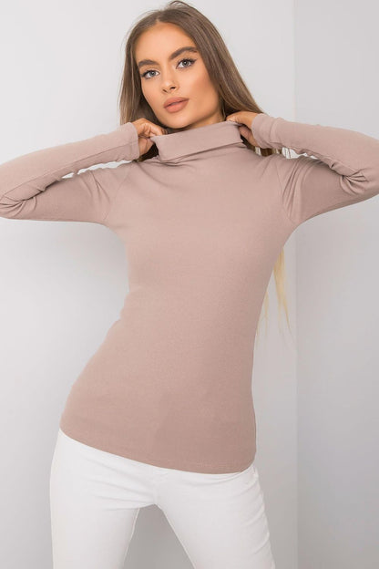 Luxurious fitted beige cotton turtleneck, model posing with a fashionable look, showcasing long sleeves and a sophisticated silhouette.