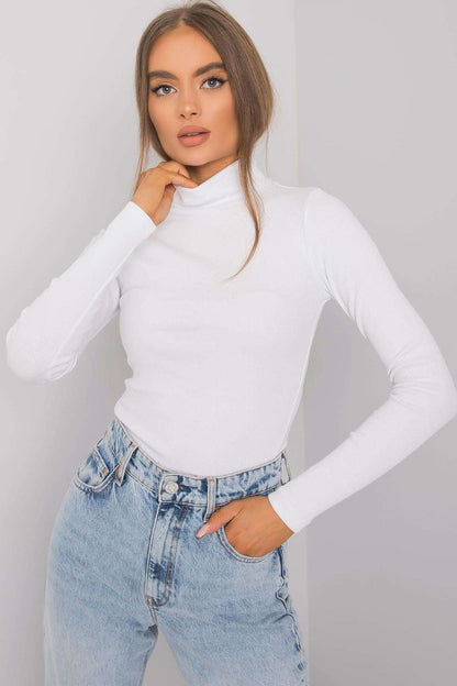 Elegant model showcasing a fitted white cotton turtleneck, styled with high-waisted light blue denim jeans, perfect for luxurious seasonal layering.