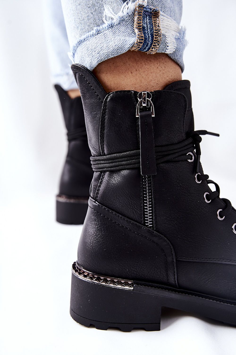 Close-up detail of luxurious black worker boots with dual zippers and decorative heel elements, designed for both comfort and style.