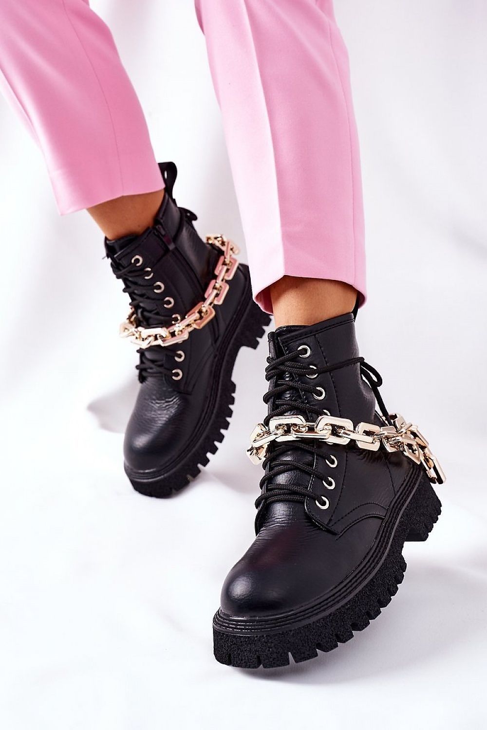 Luxury women's eco-leather black boots featuring a stylish side zipper and gold chain accessory, paired with chic pink trousers.