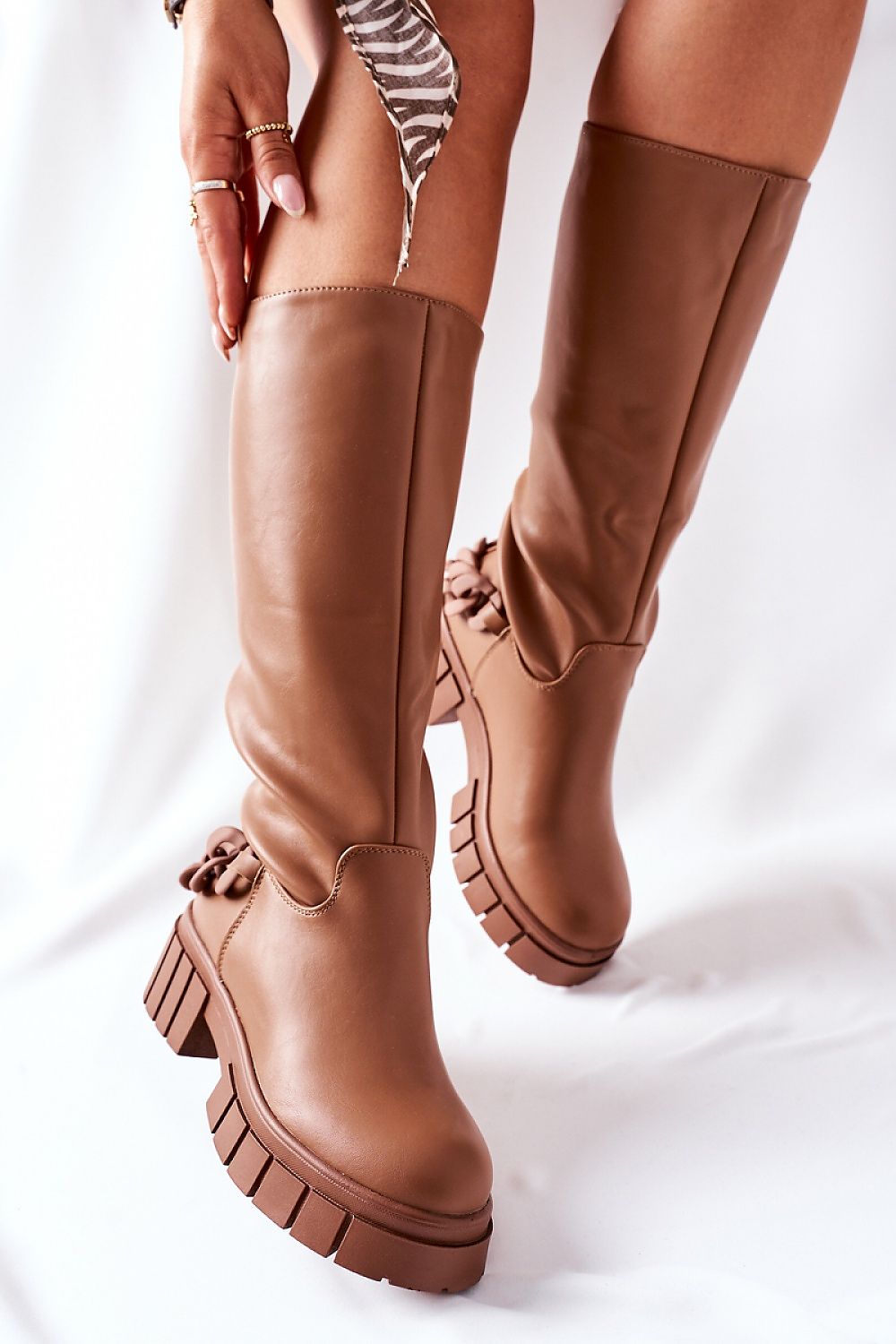 Elegantly styled luxurious brown over-the-knee stretch fabric boots featuring insulated interior and chic detailing, worn by a model. Perfect for adding a touch of sophistication to any outfit.