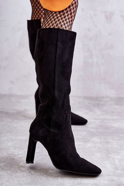 Chic black eco-suede knee-high boots with a stylish block heel, highlighting the soft texture and modern silhouette, paired perfectly with fishnet tights for a fashionable look.