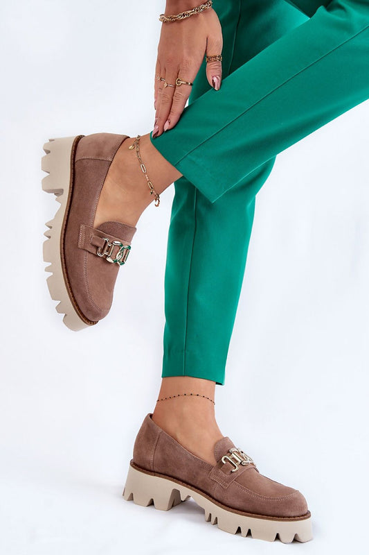 Chic suede leather slip-on shoes with a stylish chain decoration, showcased with green trousers for a fashionable look.