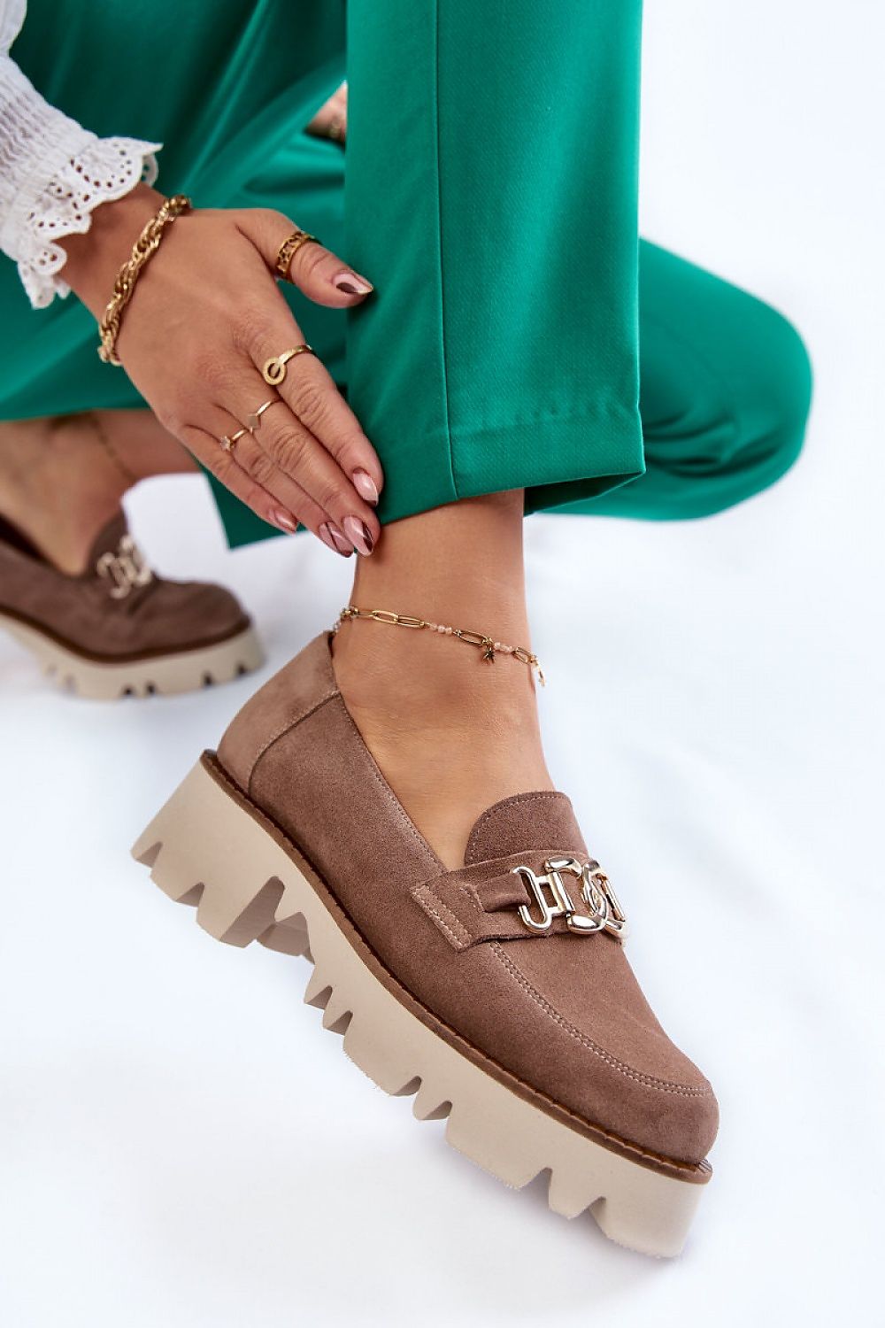 Elegant luxury suede leather half shoes in a chic slip-on design. Featuring a stylish decoration and a comfortable 5cm heel, these shoes are perfect for sophisticated stylings. The model is showcased with green tailored trousers, highlighting the shoes' versatile appeal.