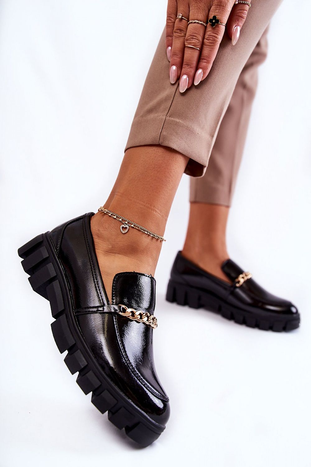 Close-up of luxurious half shoes in eco leather with a unique chain design, perfectly paired with fashionable beige attire.
