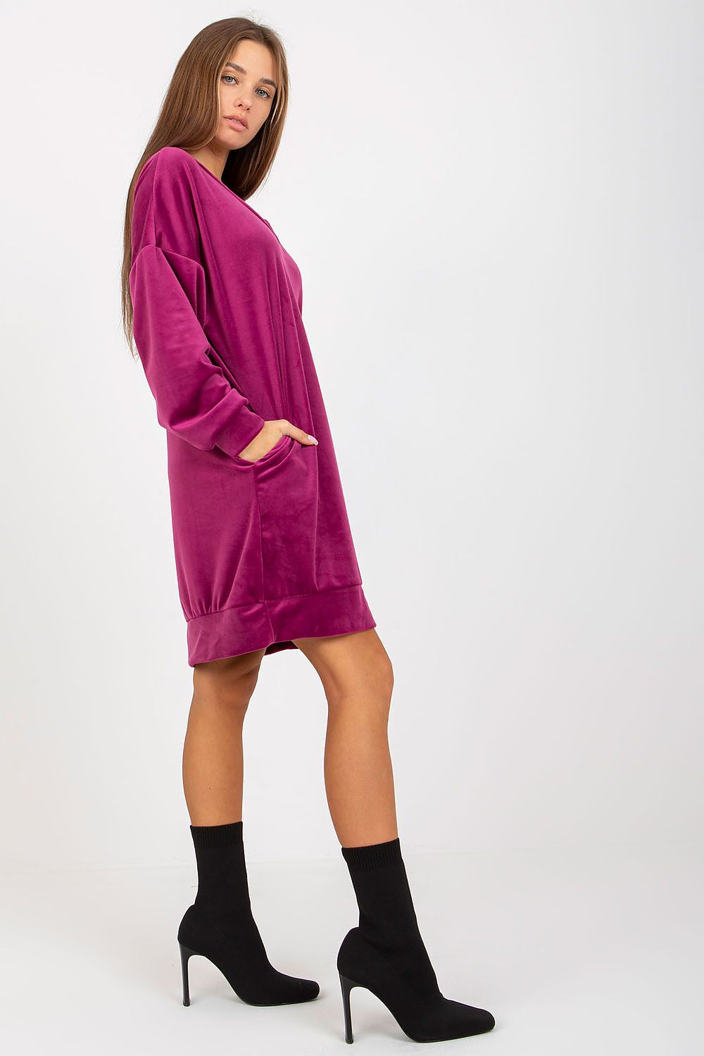 Side view of a magenta velour dress featuring a heart neckline and pockets, paired with stylish black ankle boots for an elegant appearance.