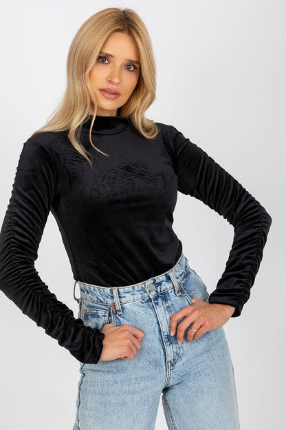 Elegant black velour blouse featuring long sleeves with chic creased details and a stylish stand-up collar, modelled with relaxed denim.