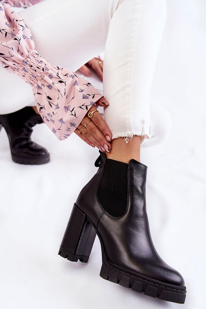 Elegant luxury women's trapper heel boots in high-quality black leather, featuring a sturdy heel and platform, paired with chic white jeans and a soft floral top, ideal for stylish autumn outfits.