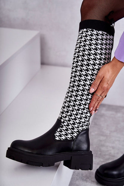 Close-up of luxurious black eco leather thigh-high boots paired with houndstooth fabric. Showcasing a comfortable flat heel, ideal for stylish and warm winter fashion.