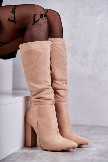 Elegant luxury pointed toe Cossack heel boots in soft beige suede, featuring a zippered front and warm insulation, styled elegantly with fishnet tights. Perfect for versatile fashion, ideal for both dresses and skirts.