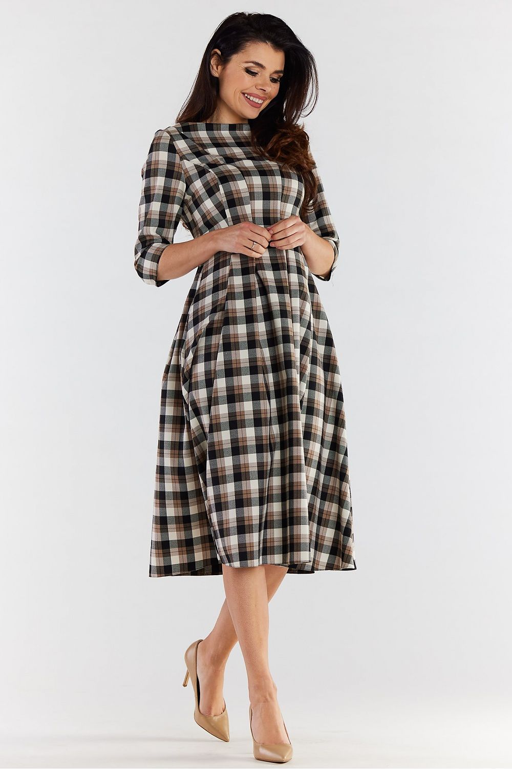 Charming woman in a checkered midi dress with a flared design, presenting a refined look complemented by classic nude heels, ideal for both work and formal events.