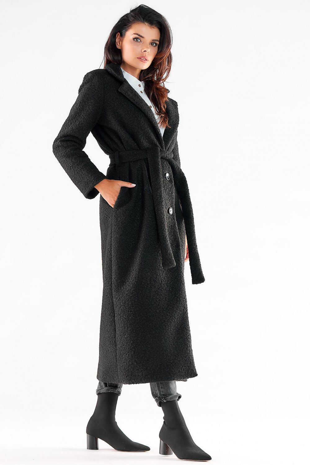 Sophisticated side profile of a woman wearing an Awama black maxi coat, emphasising its stylish belt and tailored features for an upscale look.