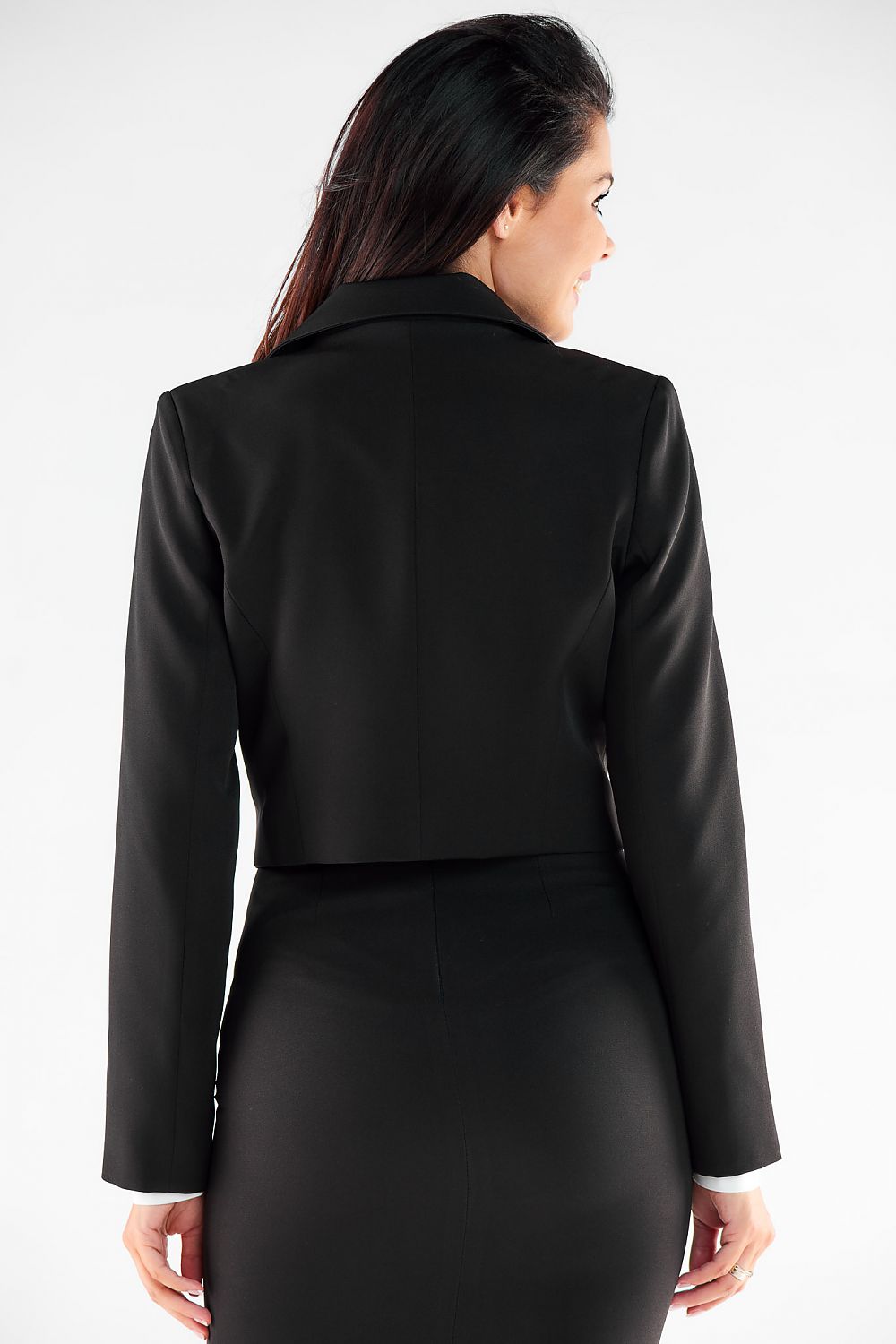 Back view of a stylish woman in a cropped black button jacket, highlighting the exquisite tailoring and design that complements her silhouette.