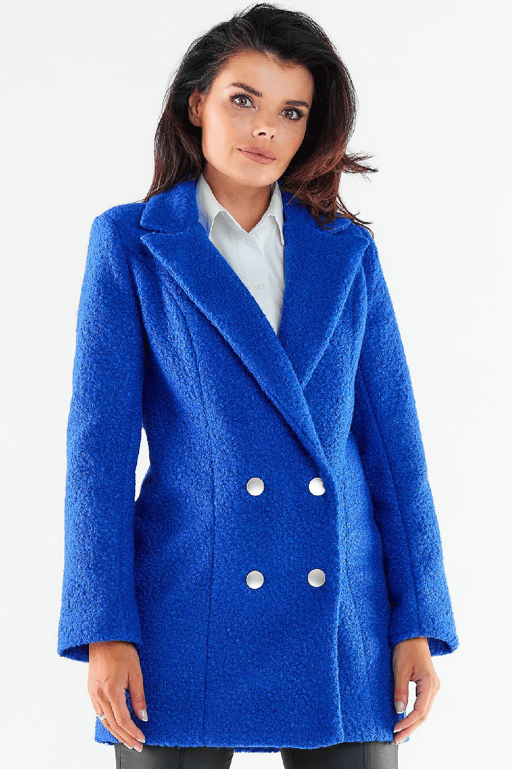 Sophisticated woman modeling a vibrant blue double-breasted coat with shiny buttons, radiating chic style and warmth.