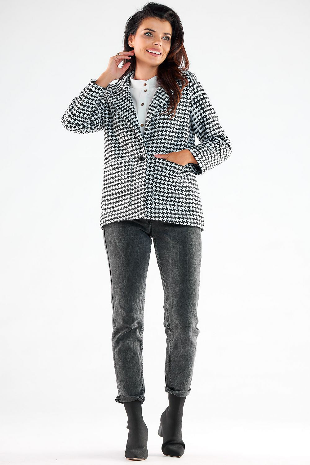 Graceful model showcasing a fashionable Awama houndstooth jacket with elegant button details and square pockets, styled effortlessly with dark jeans and ankle boots, embodying modern luxury.