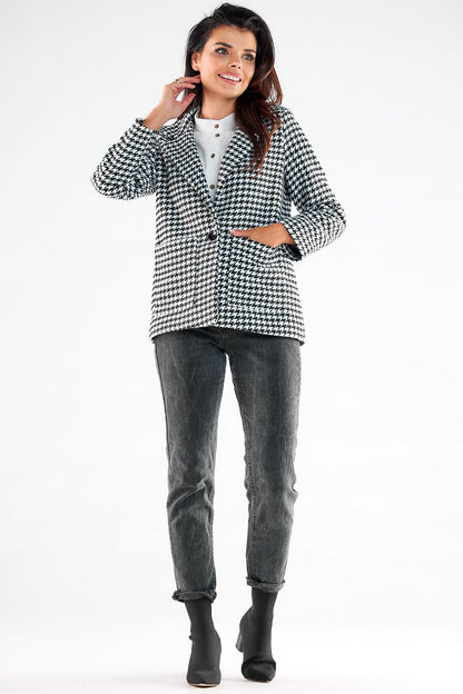 Graceful model showcasing a fashionable Awama houndstooth jacket with elegant button details and square pockets, styled effortlessly with dark jeans and ankle boots, embodying modern luxury.
