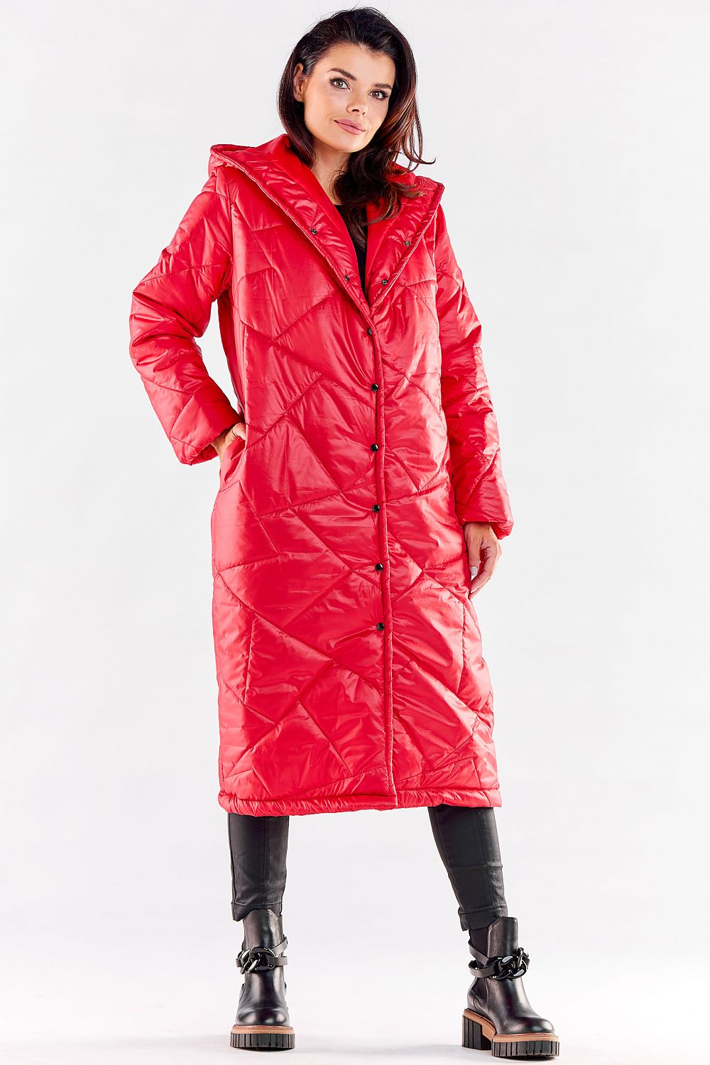 Luxury long quilted coat in vibrant red, featuring a large hood and elegant pockets, designed for autumn and winter wear. Styled with black leather trousers and chunky boots.
