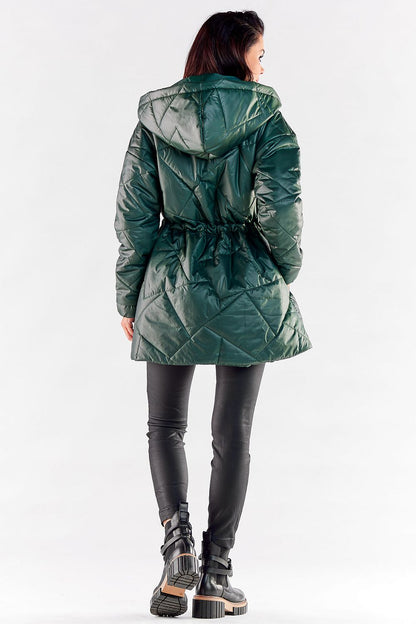 Elegant woman wearing a luxurious quilted hooded jacket in green, showcasing adjustable waist detail, perfect for windy days.
