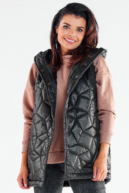 Elegant model wearing a black quilted hooded vest by Awama, complemented with a soft pink sweater, exuding sophistication and warmth for autumn styling.