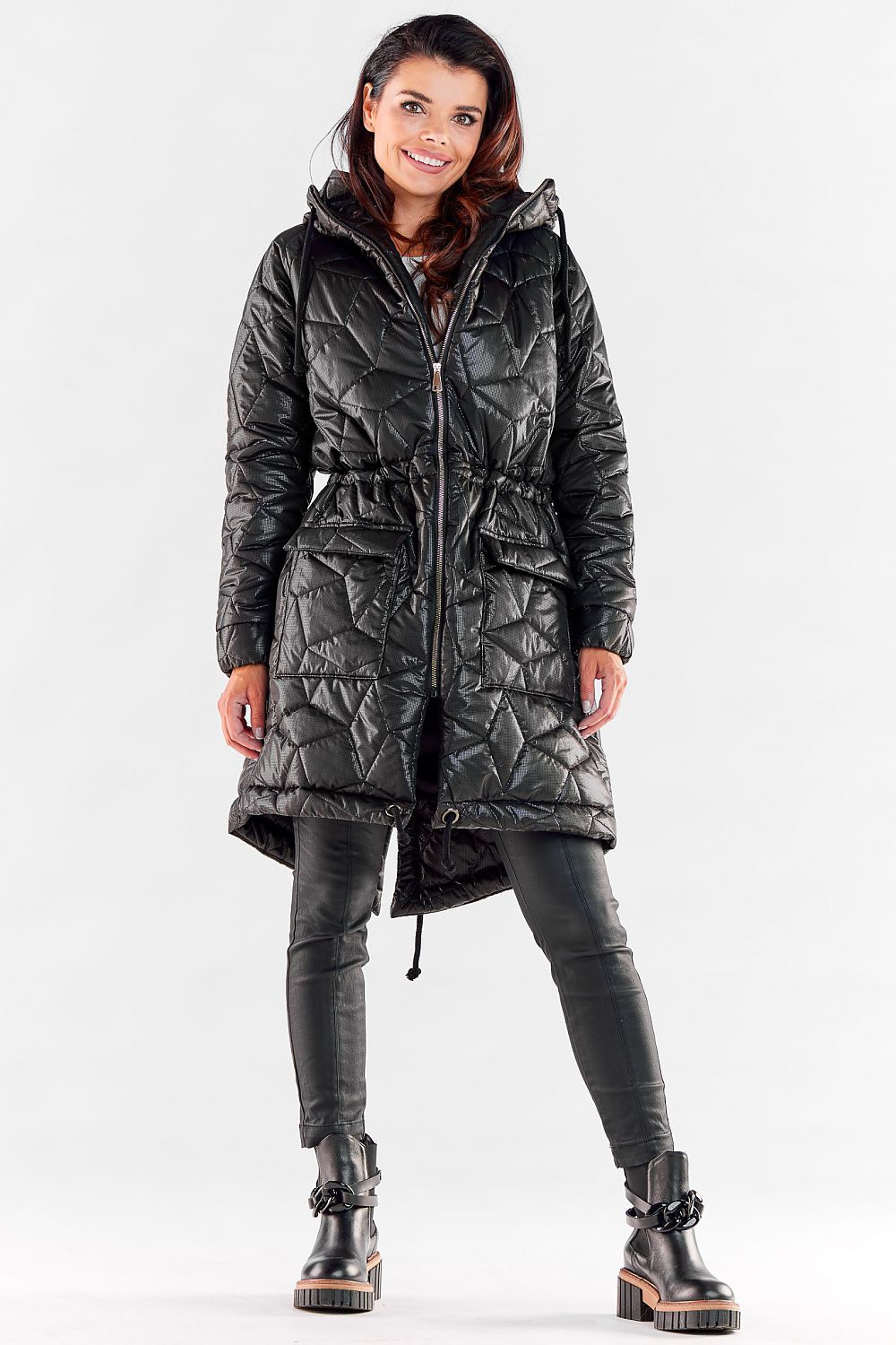 Chic woman in a black knee-length quilted jacket with a stylish hood and drawstring waist, ideal for urban elegance in winter.