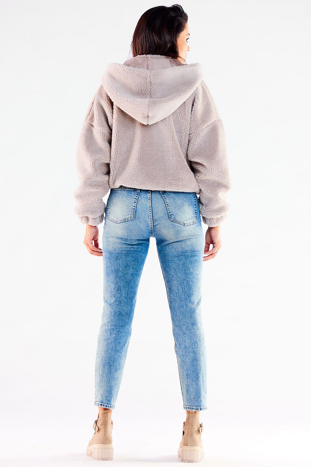 Stylishly modern light beige zippered hooded jacket from the back, showing a snug fit, paired with elegant blue denim.
