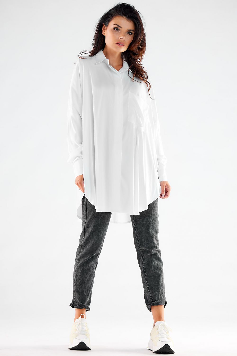 Stylish women's oversized white shirt with long sleeves, paired with grey slouchy trousers and sneakers, epitomising contemporary luxury and effortless elegance.