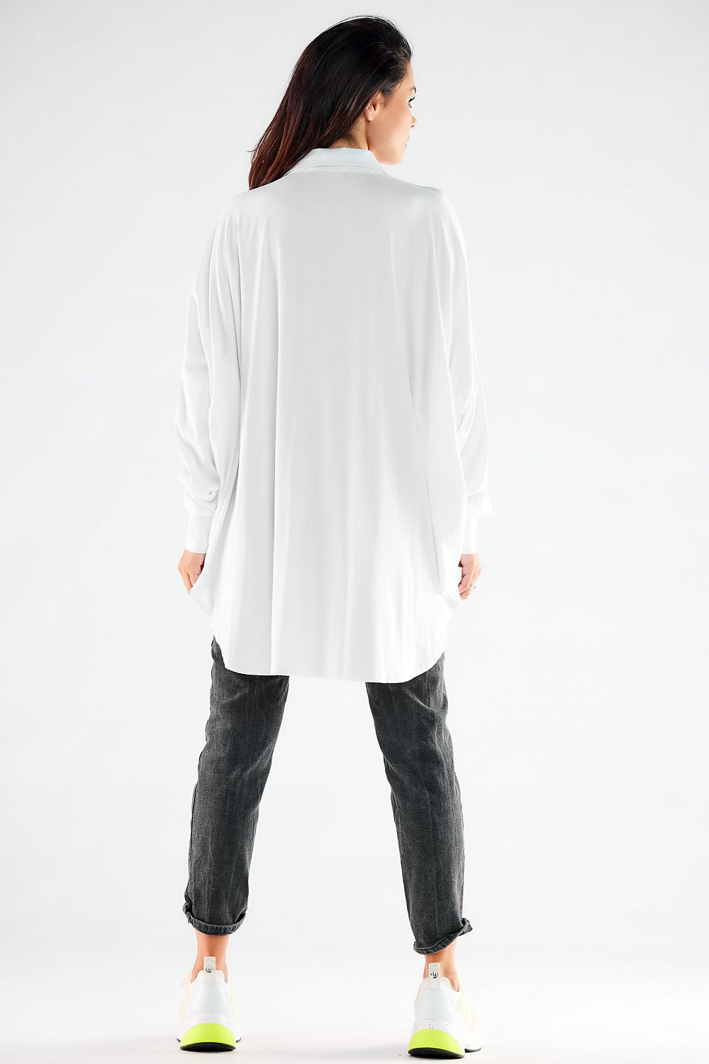 Elegant women's long sleeve oversized shirt in white, showcasing a loose fit design, styled with casual grey jeans, ideal for versatile fashion choices.
