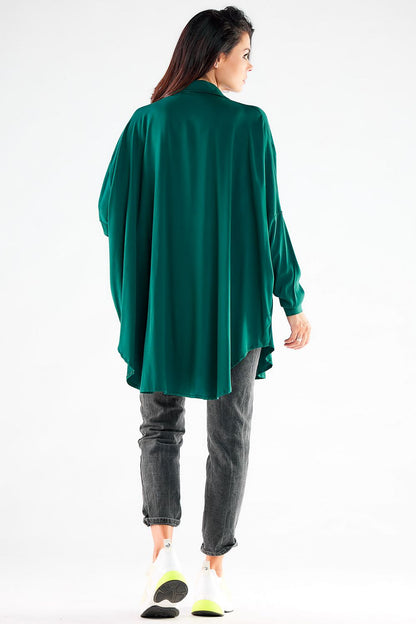 Luxurious women's green oversized shirt, embodying a stylish silhouette and effortless elegance, complemented by casual grey jeans, perfect for modern fashion.
