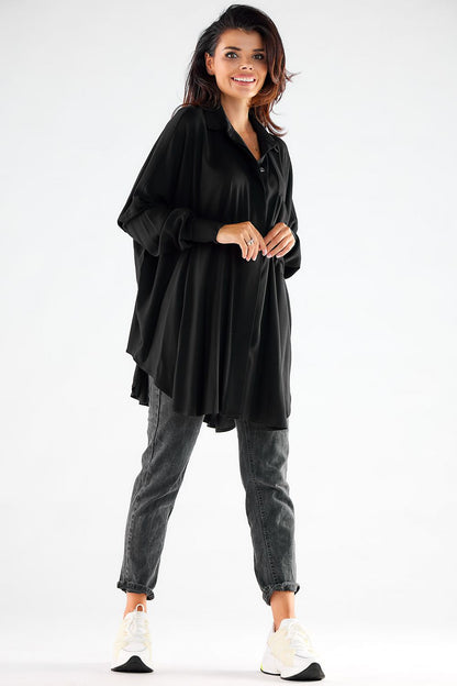 Stylish woman in a black oversized long sleeve shirt paired with grey jeans and white sneakers, showcasing versatile fashion with a loose fit and feminine silhouette.