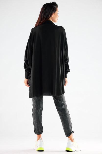Back view of a fashionable black oversized long sleeve shirt on a woman, styled with grey jeans and white sneakers, epitomising effortless chic and comfort.