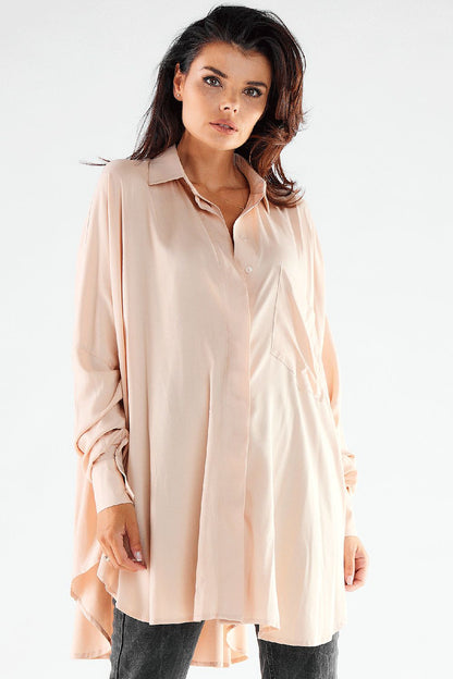Elegant woman wearing a blush pink oversized long sleeve shirt, elegantly tailored with a relaxed fit, complete with grey jeans, embodying refined femininity.