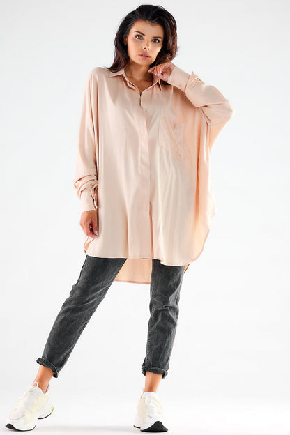 Front view of a sophisticated blush pink oversized long sleeve shirt on a woman, paired with grey jeans and white sneakers, ideal for chic casual styling.