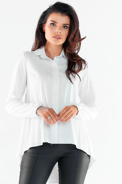Elegant long sleeve white shirt with an extended back and elastic cuffs, styled for urban sophistication, showcased on a model in a luxurious setting.