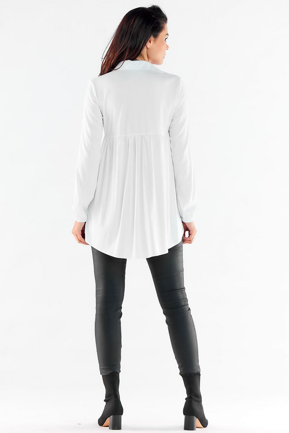 Stylish back view of a long sleeve white shirt with a relaxed fit and elastic cuffs, styled with elegant imitation leather pants for urban elegance.