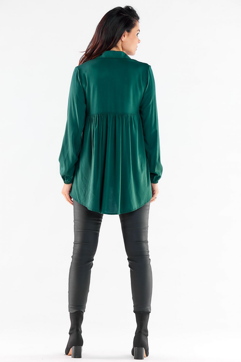 Elegant long sleeve green shirt with extended back and elastic cuffs, styled with imitation leather pants, epitomizing urban luxury.