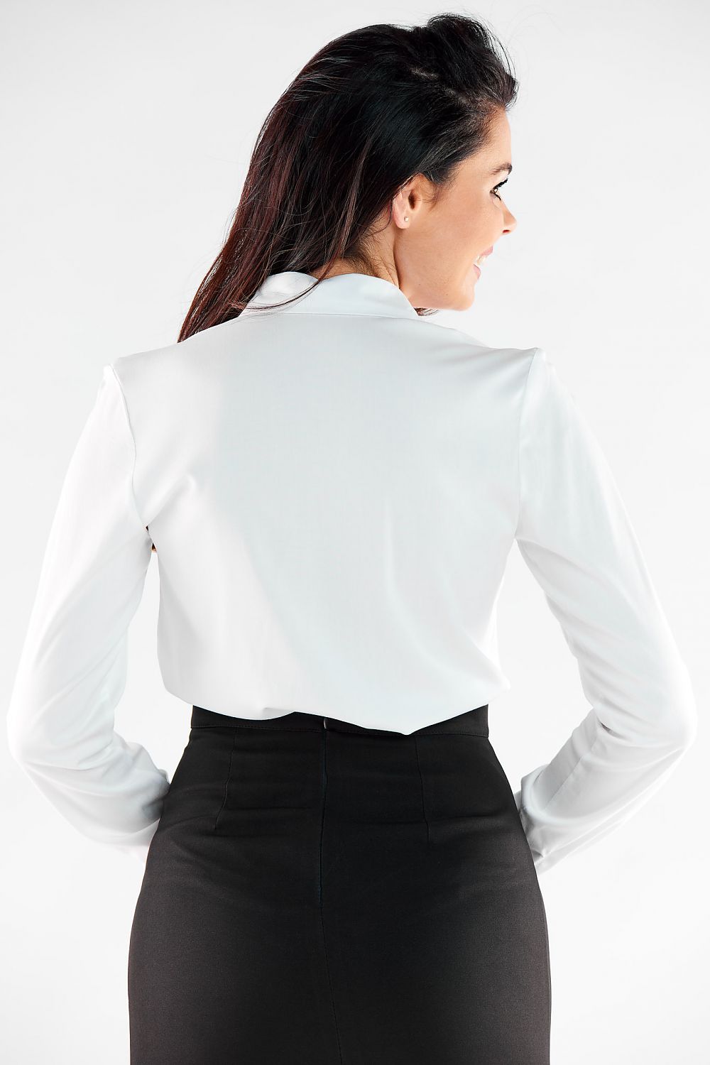 Rear view of a woman wearing an exquisite long sleeve white shirt by Awama, highlighting its tailored fit and luxurious fabric, elegantly paired with a black skirt.
