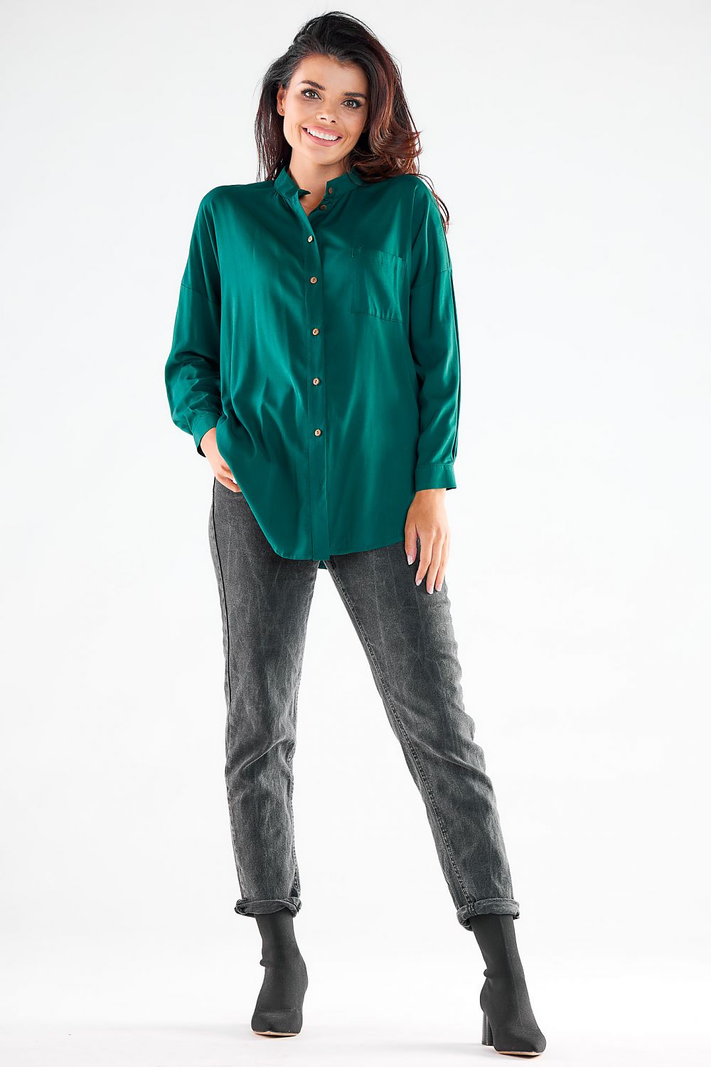 Charming model presenting a luxurious green long sleeve buttoned shirt with a stylish extended back, complemented by trendy jeans and ankle heels from Awama.