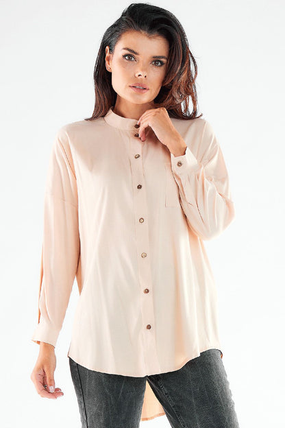 Sophisticated light peach long sleeve buttoned shirt, featuring an extended back, modeled with a graceful pose.