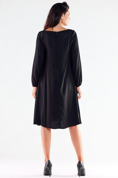 Refined black trapezoidal daydress featuring long sleeves and an elegant cut, displayed from the back to highlight its flattering design.