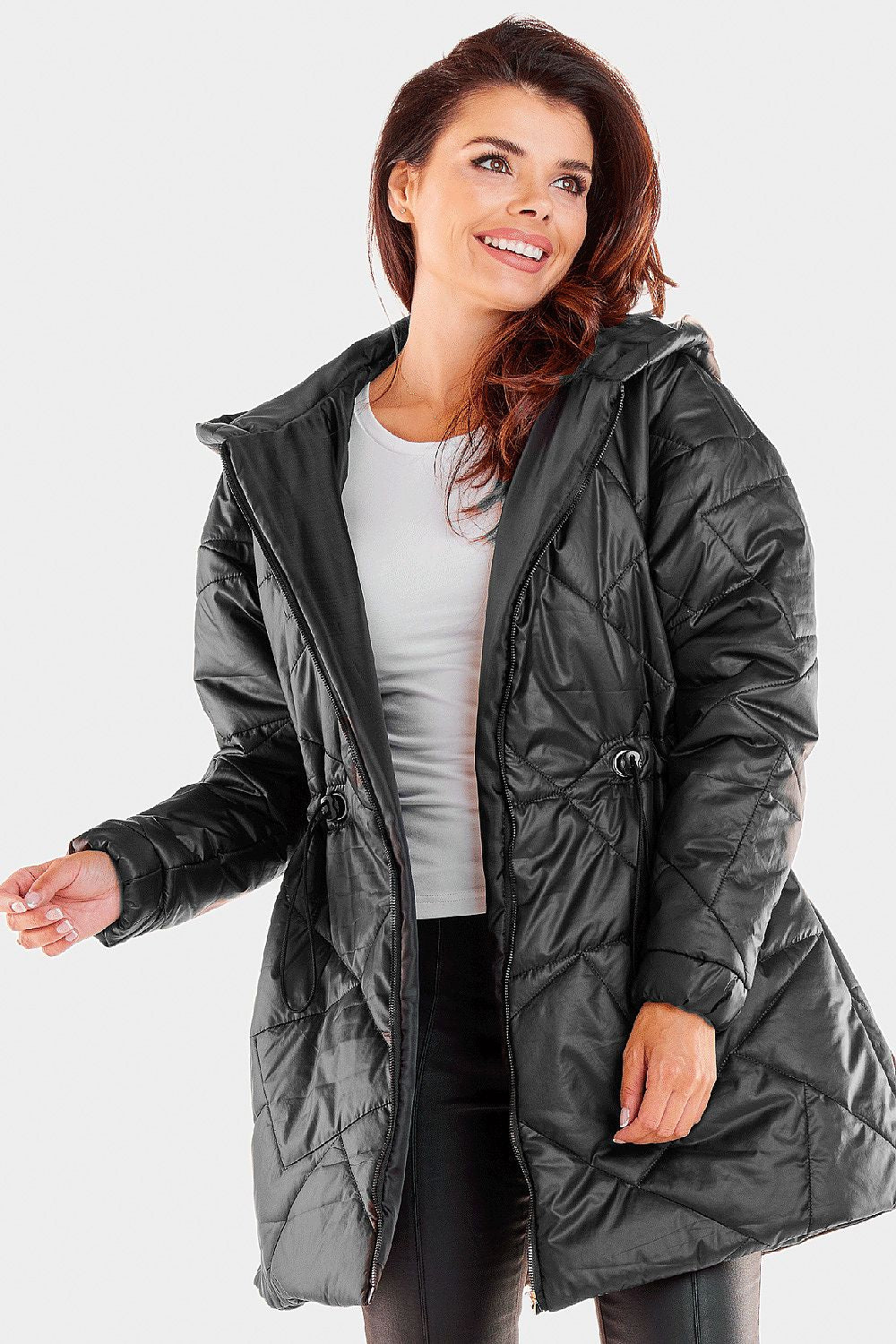 Stylish woman smiling while wearing a chic black quilted hooded jacket, featuring a fitted silhouette and premium polyester fabric.