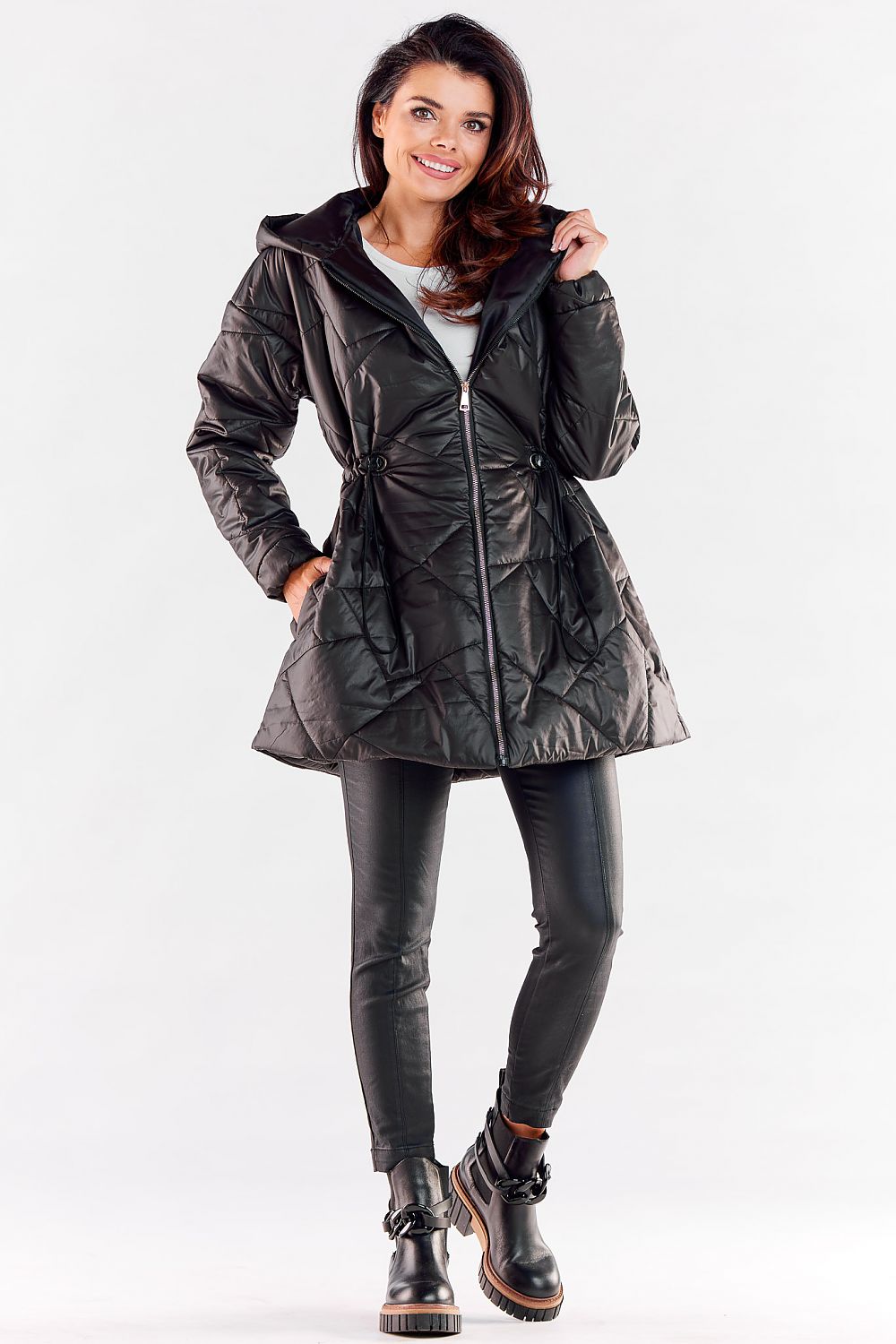 Confident woman in a sophisticated black quilted jacket, designed with a cinched waist and stylish hood, ideal for modern fashion.