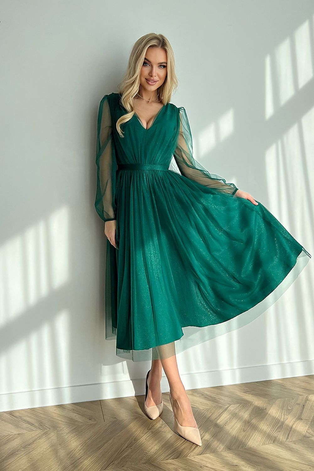 Chic green midi dress with a flared layered skirt and sheer long sleeves, elegantly twirling to showcase its lavish design, suitable for special events.