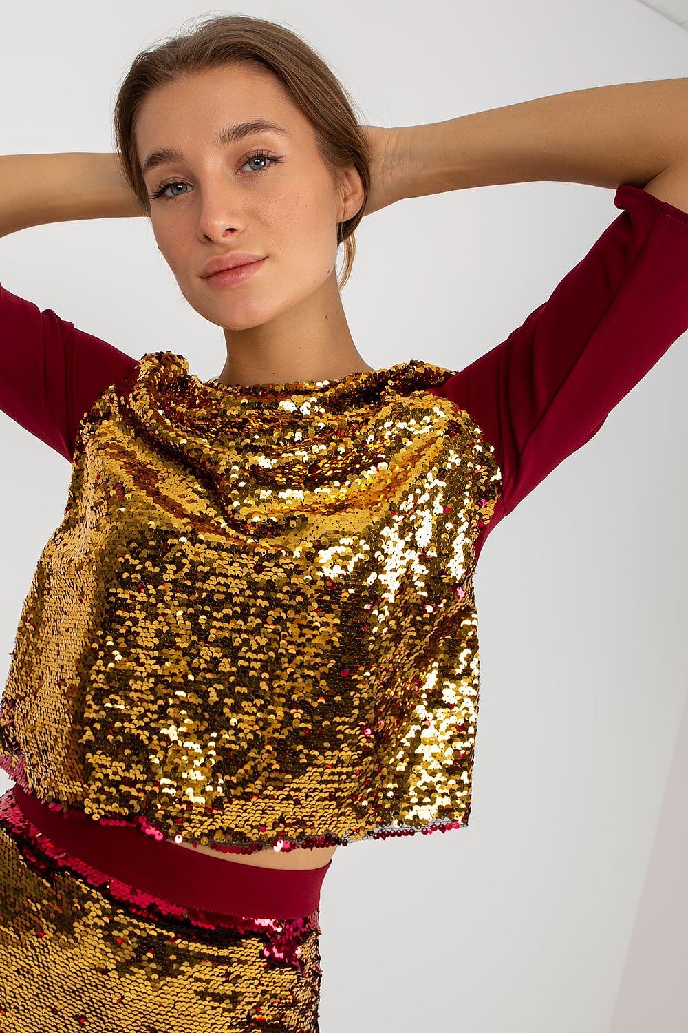 Elegant blouse with sequins in gold and maroon, showcasing a model with a radiant expression, perfect for luxury occasions.