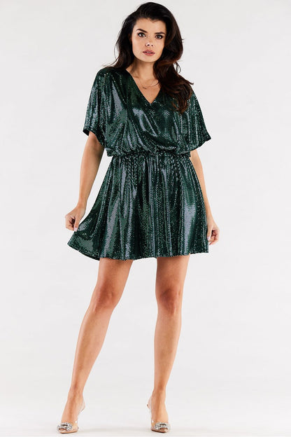 Sophisticated portrayal of a model in a stunning green flared dress with short sleeves, accentuated by an elastic waist, perfect for glamorous occasions.