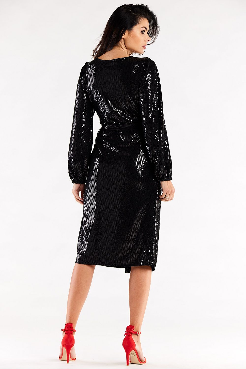 Back view of a luxurious black evening dress with crinkled long sleeves and a cinched waist, complemented by radiant red heels, epitomising elegance and style.