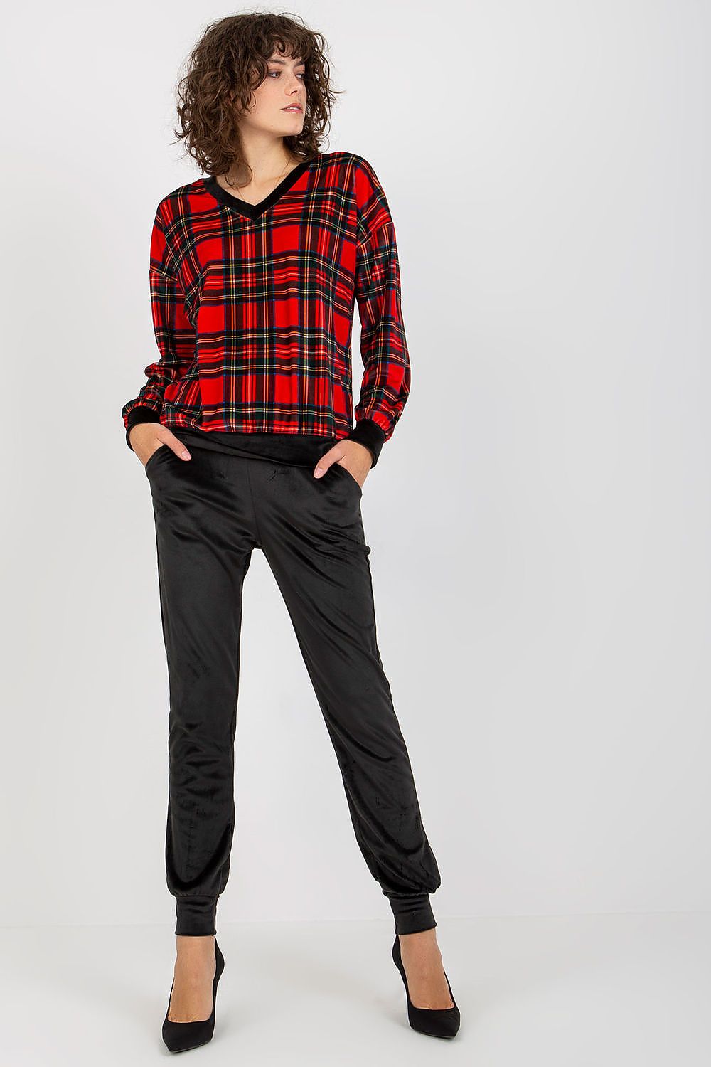 Elegant ladies' velour set featuring a striking checkered blouse in vibrant red and black paired with chic black pants, model posing confidently.