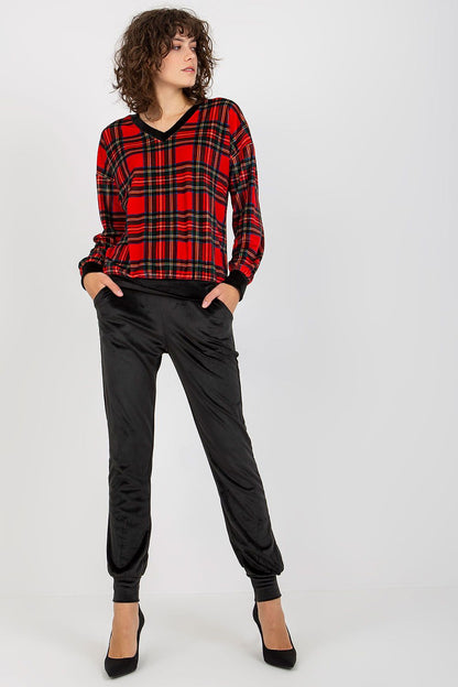 Elegant ladies' velour set featuring a striking checkered blouse in vibrant red and black paired with chic black pants, model posing confidently.