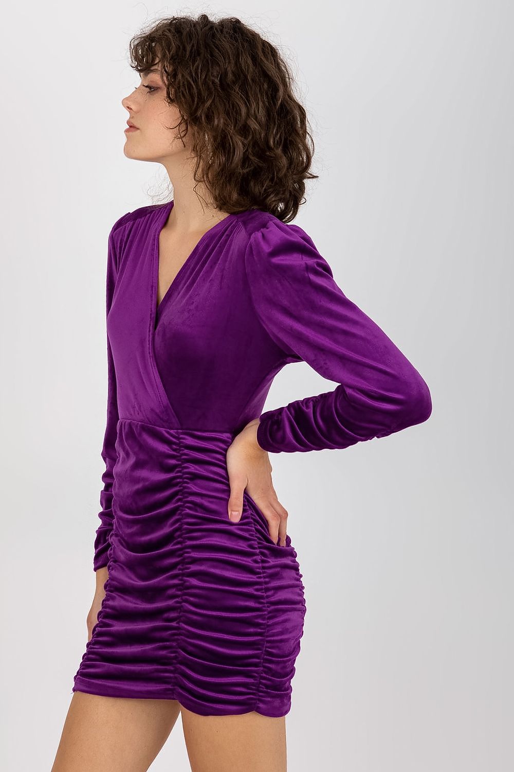 Side profile of a fashionable purple velour evening dress with a flattering silhouette and ruched elements, perfect for upscale occasions.