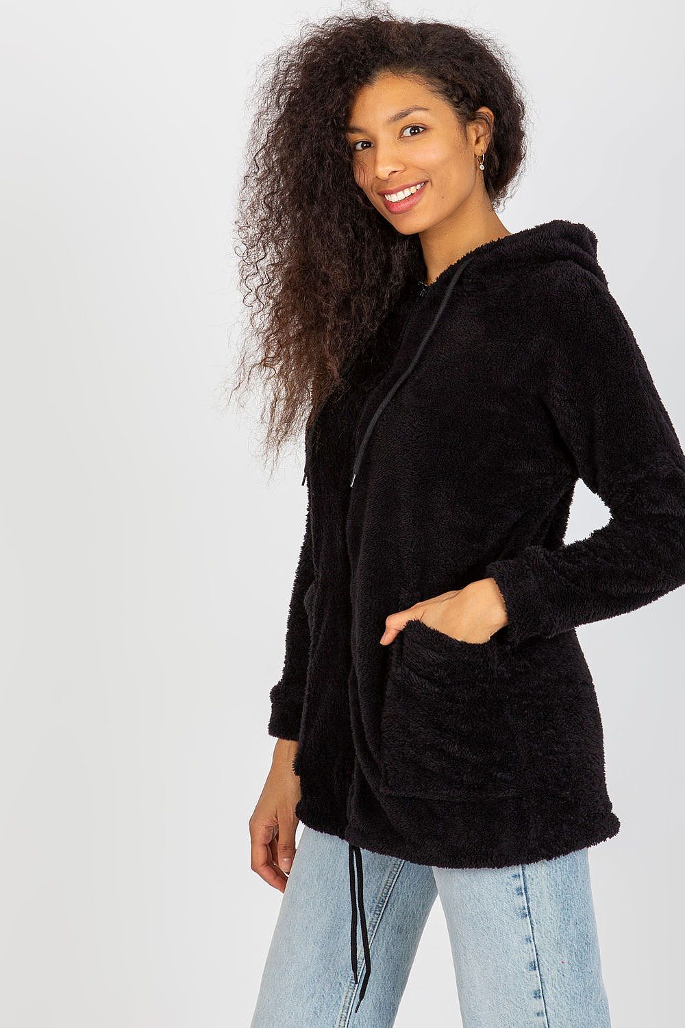 Side view of a sleek black fur zip-up sweatshirt with a hood and handy slip pockets, showcased by a smiling woman with voluminous curly hair.