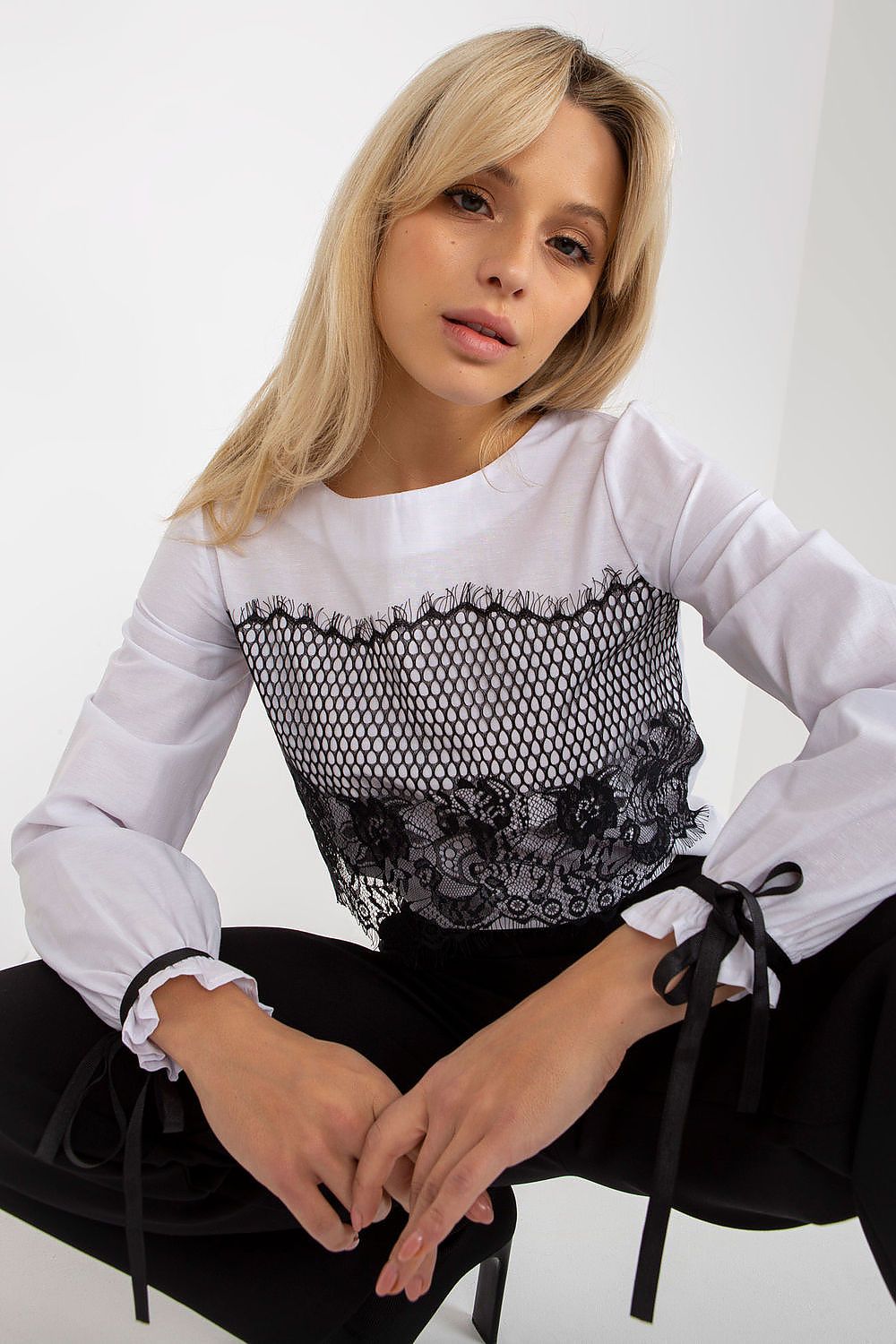 Elegant woman modelling a luxury cotton blouse featuring decorative lace, with long sleeves and stylish ties, perfect for upscale occasions.